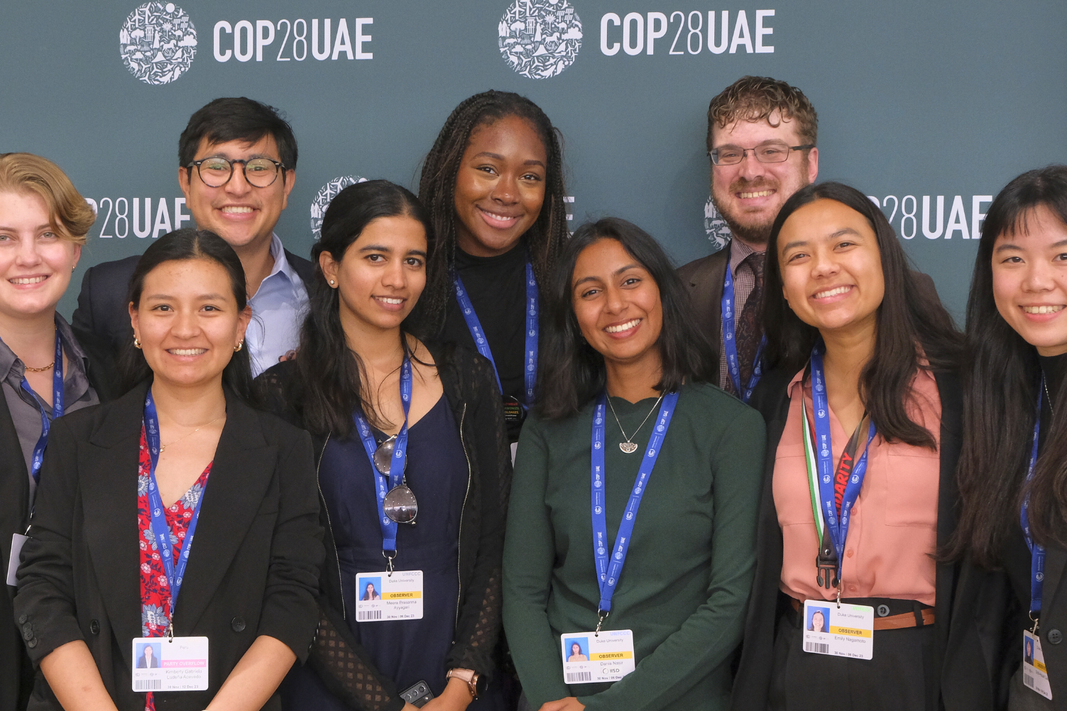 Duke students smiling in front of COP28UAE backdrop.